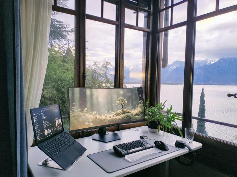 A lovely corner desk setup with a lake and mountains out the windows.