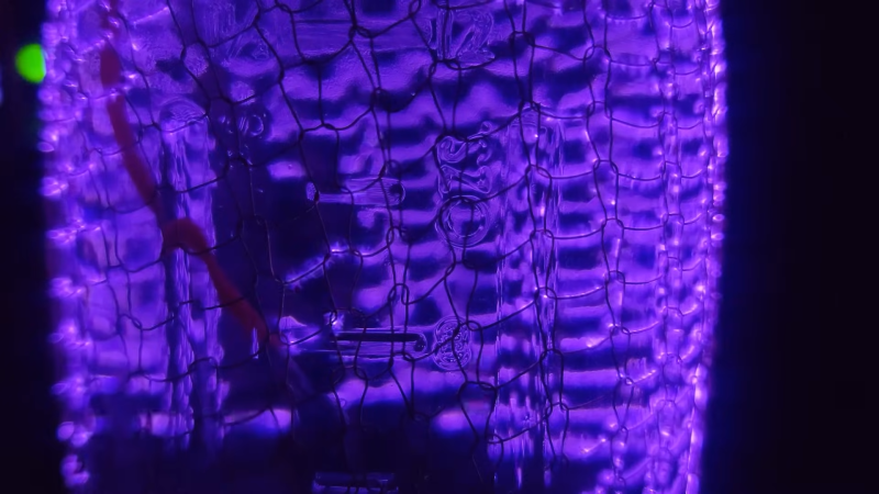 Grid overlayed onto a mason jar. Across the grid are high voltage purple coronas.