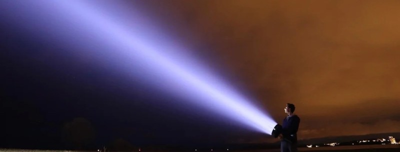 A man aims the LED flashlight into the night sky.
