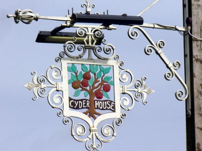 A hanging sign surrounded by ornate metalwork, with the legend "Cyder house".
