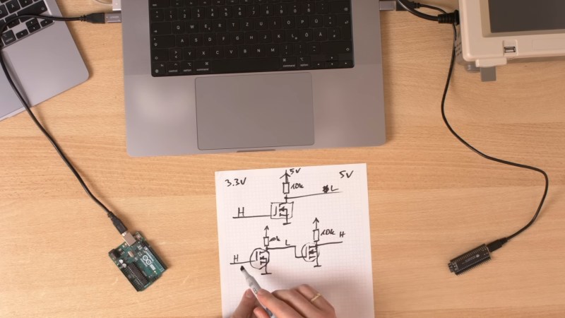 A circuit diagram in a book on a desk with computers and microcontrollers