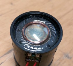 The thin plastic film of the front of a dynamic microphone, with the coil and magnet visible behind it.