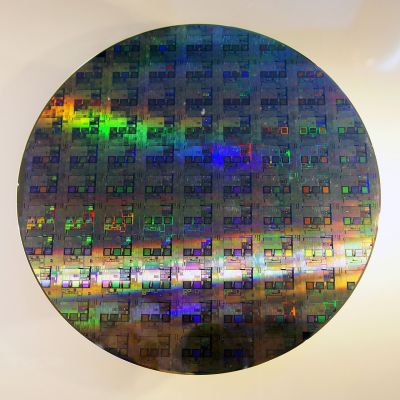 A mirror-like disc of silicon, with visible IC patterns and a rainbow pattern from diffraction.