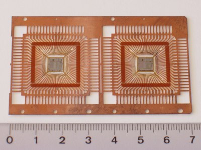 A copper sheet cut into a spiders-web-like pattern of copper fingers, which converge on the square space in the centre where the chip will go.