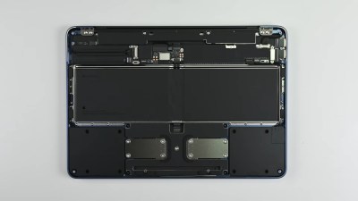 An upside down laptop with its cover removed on a grey surface. The inside of the laptop is a series of black modules connected to the frame with glorious amounts of screws and not glue!