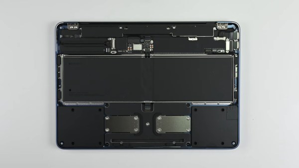 An upside down laptop with its cover removed on a grey surface. The inside of the laptop is a series of black modules connected to the frame with glorious amounts of screws and not glue!