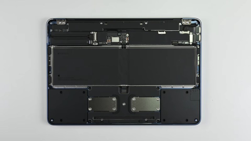 An upside down laptop with its cover removed on a grey surface. The inside of the laptop is a series of black modules connected to the frame with glorious amounts of screws and not glue!