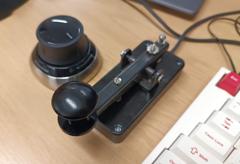 A space mouse, a telegraph key macro pad, and part of a keyboard.