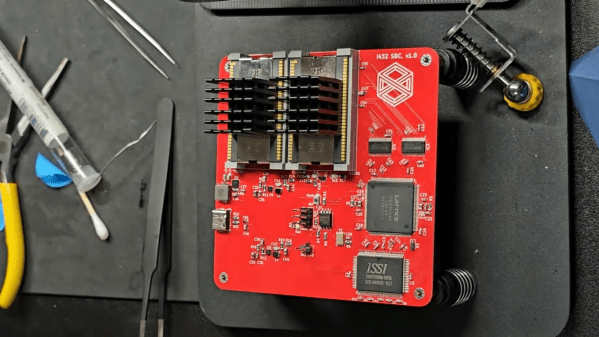 A square red circuit board is shown on a black workbench. The circuit board houses two large chips in the upper left corner, each with a large heat sink attached.