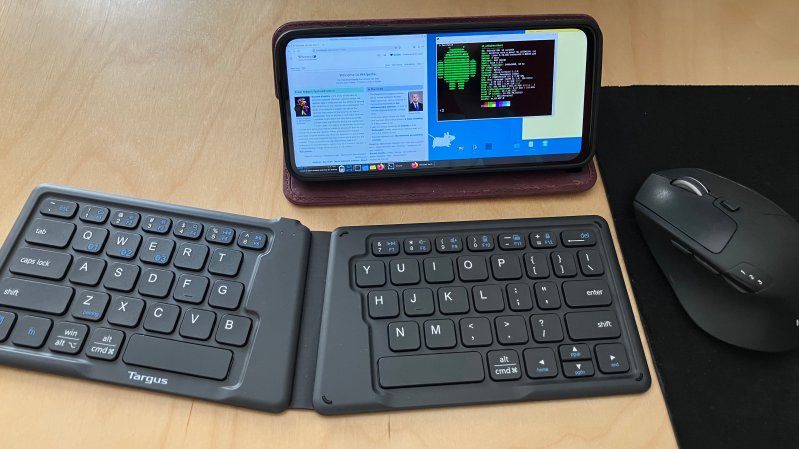 A phone running the XFCE desktop environment is placed on a desk, with a wireless keyboard in front of it.