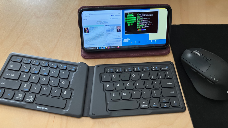 A phone running the XFCE desktop environment is placed on a desk, with a wireless keyboard in front of it.
