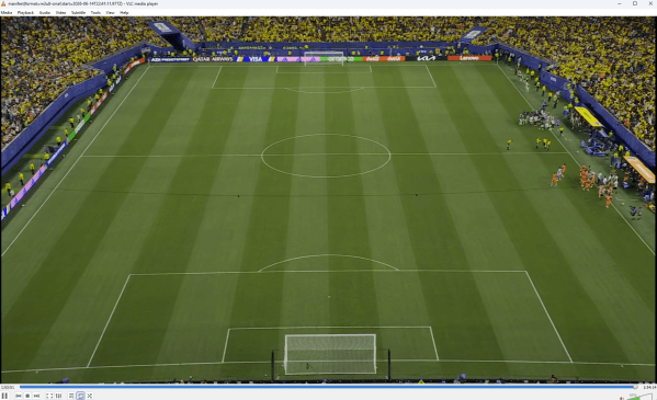 A VLC media window with a live feed of a soccer field. Players are just starting to come off the sideline to play.