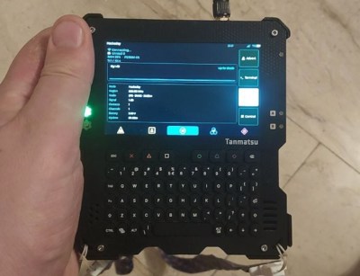 The Tanmatsu handheld computer showing a screen from the Wadamesh Meshcore app.