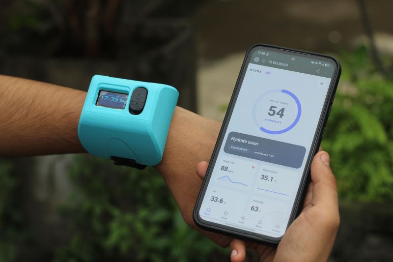 An arm and a hand: on the arm is a chunky blue box, and in the hand is a phone showing a dashboard.