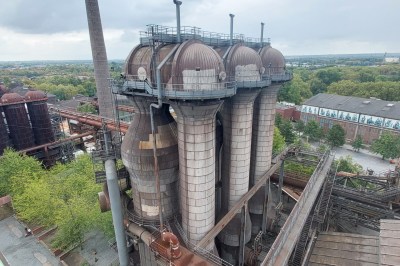 A set of huge multi-storey grey tanks surrounded by pipework and industrial plant.