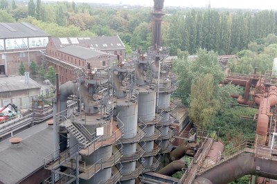 Looking down on a large industrila plant with rusty tanks and pipework.
