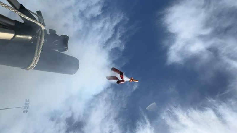 A small rocket is shown launching into the sky, with a trail of smoke leading into the mount of a black pipe. Four large plastic pieces are falling away from below the rocket.